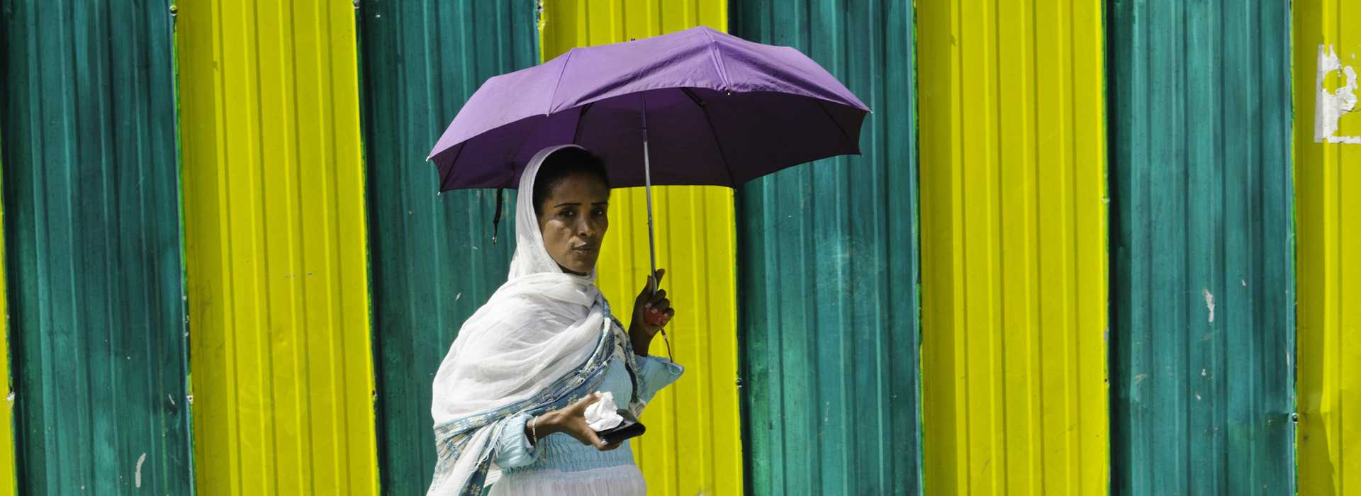 Woman walking past colourful fence