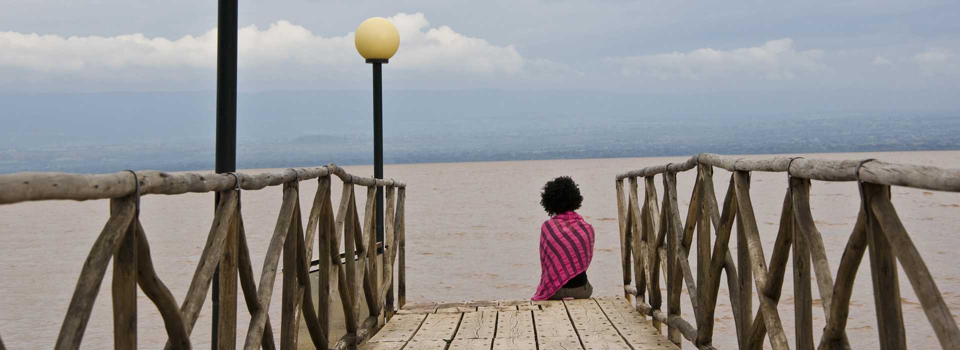 Person sitting on walkway looking at Lake Langano