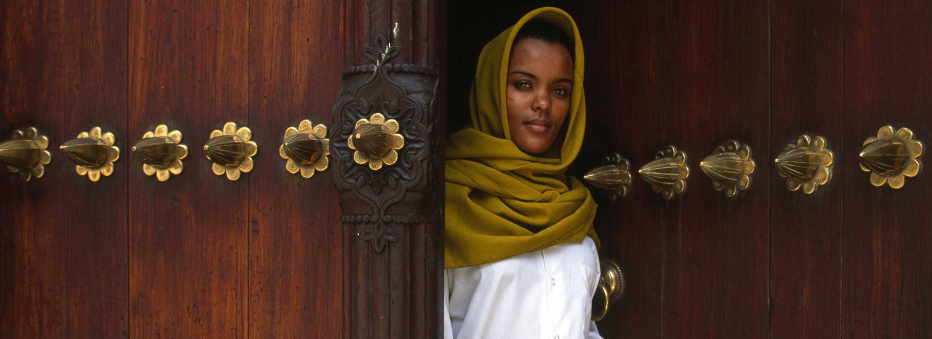 Lady at ornate door in Stone Town, Zanzibar