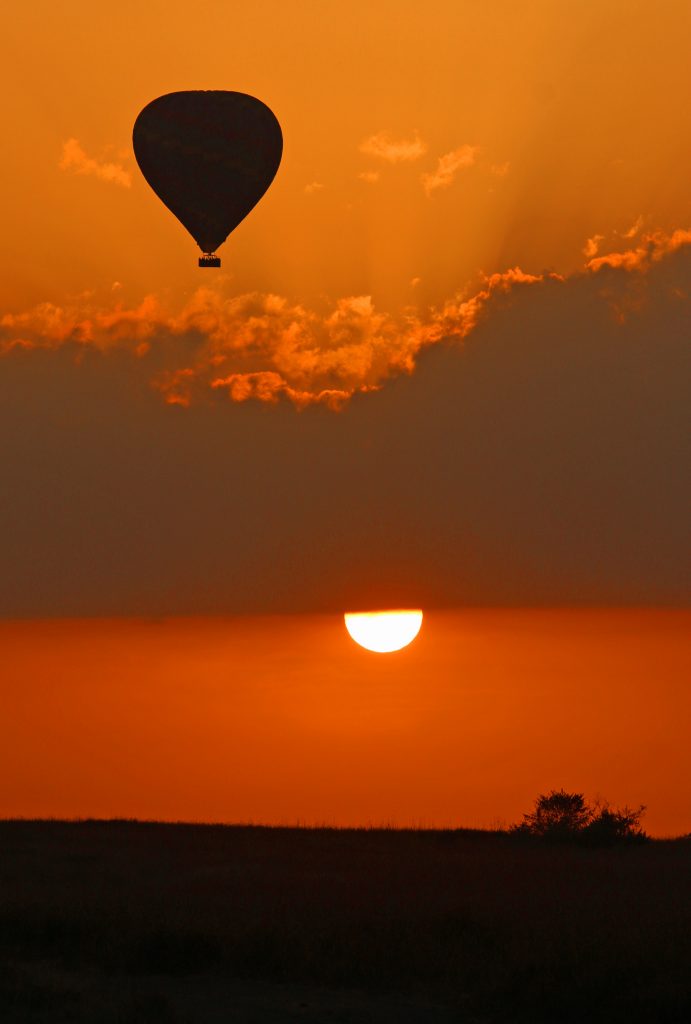 Sunrise Ascent: the rising sun and a hot-air balloon in the Mara.