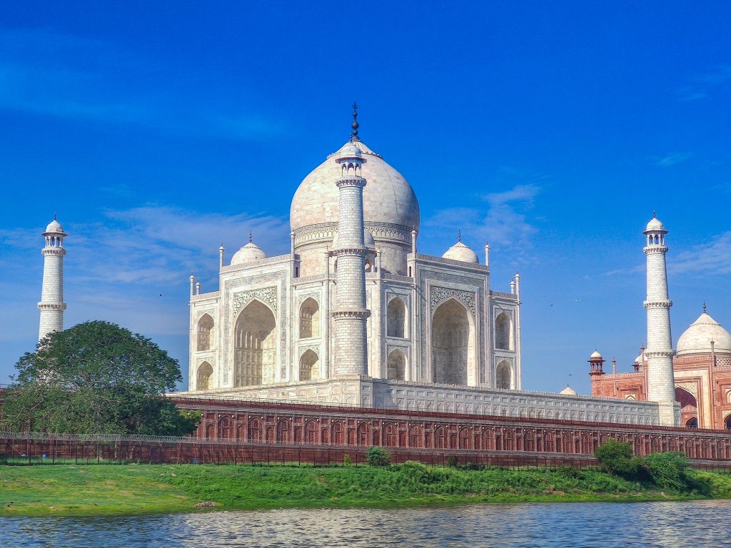 Tah Mahal with a brilliant Blue Sky and green grass and river in the foreground. 