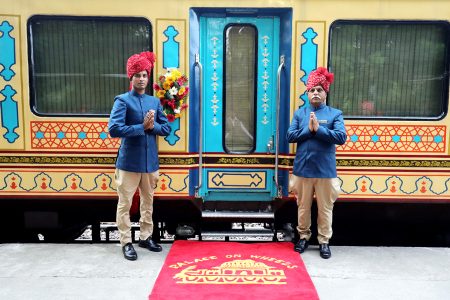 The Palace on Wheels standing at a platform with two men in turbans and traditional attire standing alongside the door to welcome guests on to the train. Source: thepalaceonwheels.com