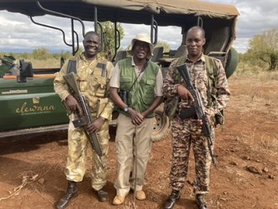 Game rangers and guides stand with guns in front of a safari vehicle in an African safari park